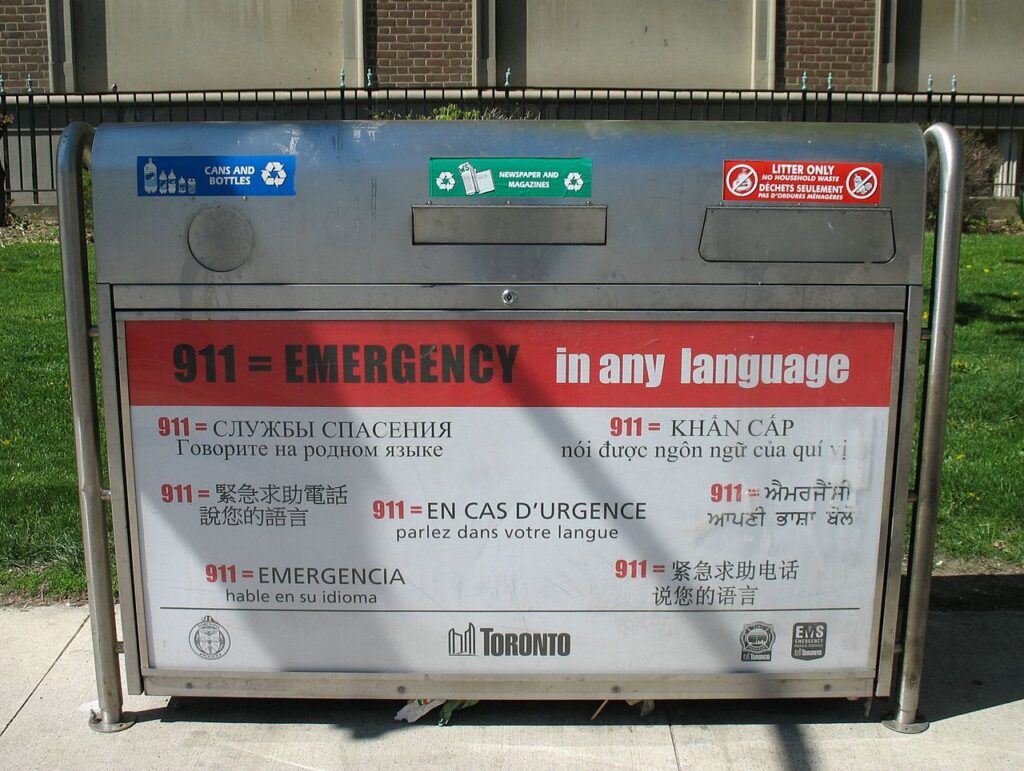 A waste receptacle in Toronto with an advert for the local multilingual emergency telephone service (from left to right and top to bottom: English, Russian, Vietnamese, Traditional Chinese, French, Punjabi, Spanish, and Simplified Chinese)